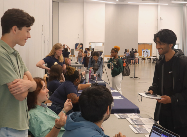 Students interact with representatives at an information table during the Experiential Learning Showcase.