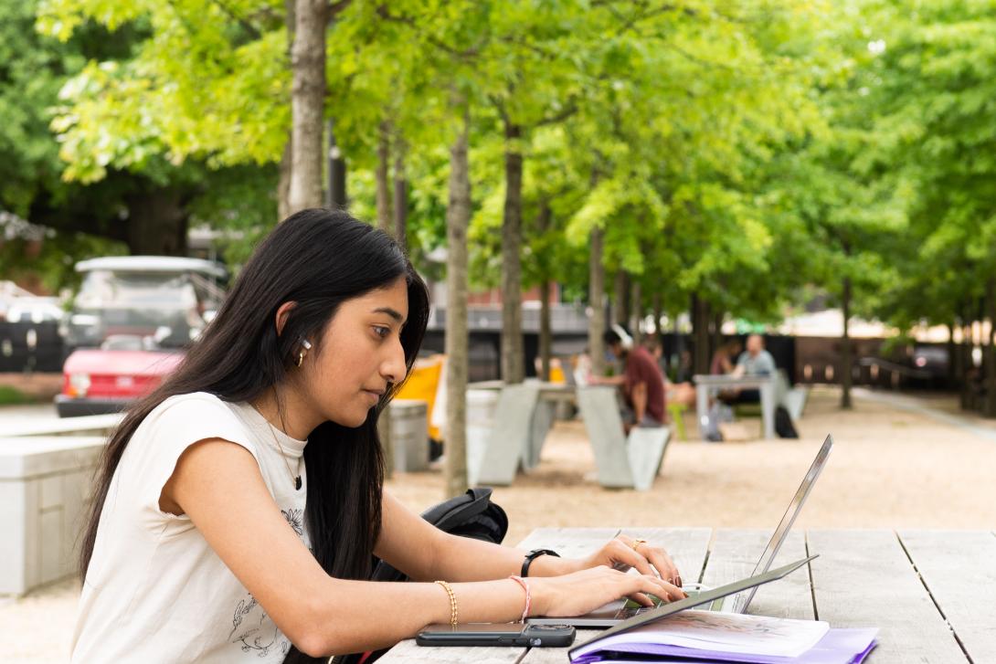 Student on her laptop on Skiles Walkway
